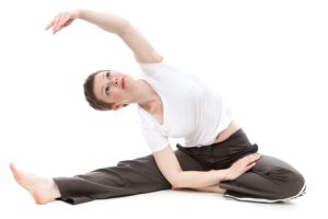 A young woman with short hair does yoga exercises in a white environment.