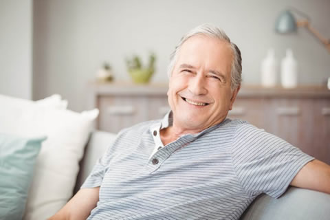 A rejoicing man sitting on a light grey couch.