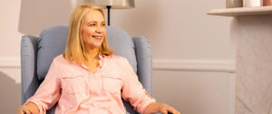 A woman sitting on a blue-grey reclining chair.