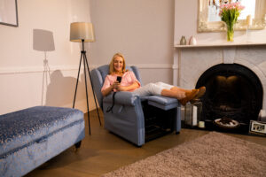 Woman sitting back in riser recliner smiling. 